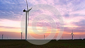 Wind turbine in an offshore wind farm in the green field against low sun on sunrise the close-up