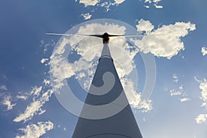 A wind turbine photographed vertically from below against a blue sky.