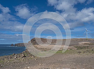 Wind turbine power plant at rocky atlantic coast in the north west of Gran Canaria with sea and cliffs, blue sky, white