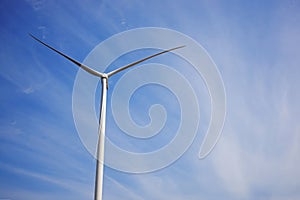 Wind turbine producing alternative energy on the background of blue sky.