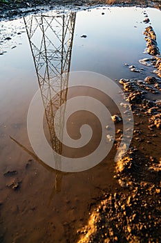 Wind turbine in the reflection of a dirty puddle. Theme of renewable energy clean power generation and sustainable energy