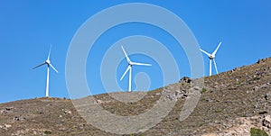 Wind turbine on a rocky hill, clear blue sky background, sunny day. Renewable power energy