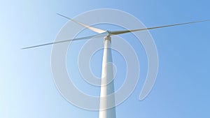 Wind turbine rotating on clear blue sky background. Local eco friendly energy wind converter farm. Green electricity