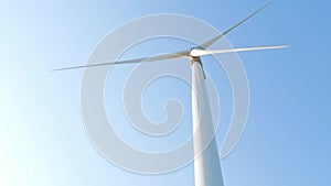 Wind turbine rotating on clear blue sky background. Local eco friendly energy wind converter farm. Green electricity