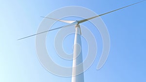 Wind turbine rotating on clear blue sky background. Local eco friendly energy wind converter farm. Green electricity