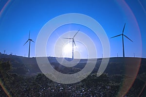 A wind turbine is silhouetted by the setting sun