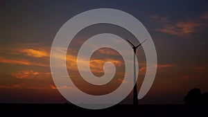 Wind turbine at sunset and colorful sky with few clouds, without audio