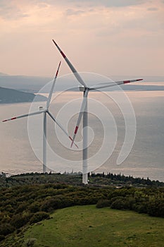 Wind turbine at sunset, on a hill with sea view.