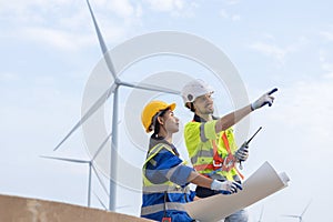 Wind turbine technician checking and maintenance at turbine station. Man and woman engineer working at energy wind generator.