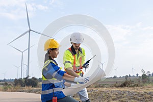 Wind turbine technician checking and maintenance at turbine station. Man and woman engineer working at energy wind generator.