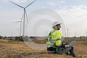 Wind turbine technicians using laptop checking and maintenance at turbine station. Man engineer working at energy wind generator