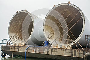 Wind turbine tower secured with chains on barge for sea transport