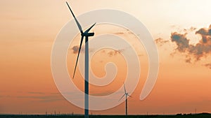 Wind turbine in wheat field at sunset, propellers of windmills on sunset sky background