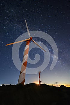 A wind turbine in a wind farm and milky way in the background