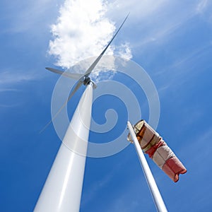 Wind turbine and windbag and white cloudagainst blue sky