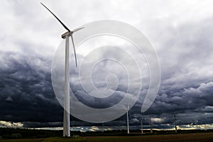 Wind turbines against dark clouds in the upcoming storm, concept