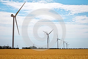 Wind turbines and agricultural field on a summer day. Energy production, clean and renewable energy