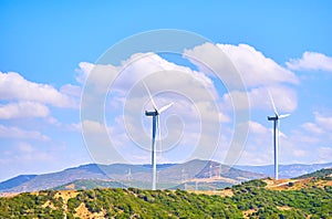 Wind turbines between an arid field and a blue sky background for copy space