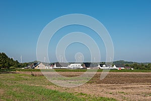 Wind turbines behind a new building settlement in rural surround