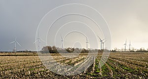 Wind turbines creating electricity out of wind energy on stubble field in rural Germany