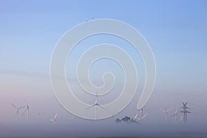 Wind turbines in early morning mist on countryside of ostfriesland in lower saxony