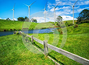 Wind turbines farm on a green grass hills