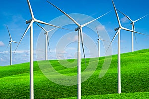 Wind turbines farm on a green grass hills.