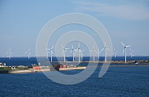 Wind turbines farm in land and water creating alternative sustainable energy. Landscabe with blue sky and copy space