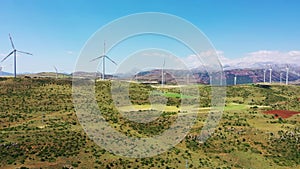 Wind turbines with a farm tractor on the field. Tractor tilling dusty fields near the base of wind turbines in Thrace