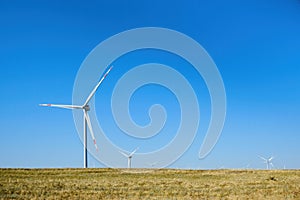 Wind turbines in the field against a blue sky in summer.