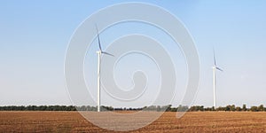 Wind turbines on field. Empty field in foreground, blue sky on background.