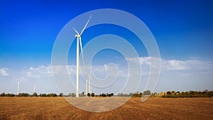 Wind turbines on field. Empty field in foreground, blue sky on background.