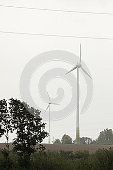 Wind turbines field in a stormy day with strong wind and rain. Wind farm eco field. Green ecological power