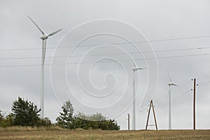 Wind turbines field in a stormy day with strong wind and rain. Wind farm eco field. Green ecological power