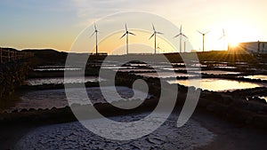 Wind turbines generating electricity energy silhouettes, salt pans landscape at sunset