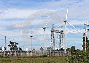 Wind turbines generating electricity with high voltage electrical power pylon substation