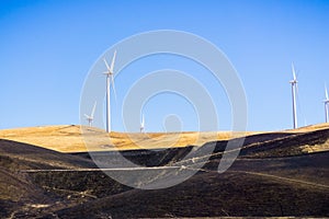 Wind turbines on the golden hills of east San Francisco bay area; burnt grass in the foreground; Altamont Pass, Livermore, photo