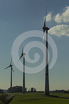 Wind turbines on green field with path. Green â€“ ecological, renewable and sustainable alternative to traditional sources of