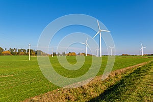 Wind turbines among a green field on sunny autumn day