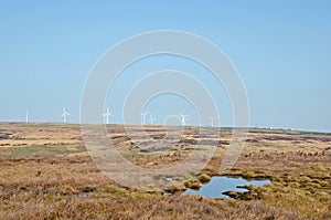 Wind turbines on high pennine moorland taken from midgley moor with peat bog ponds and pennine landscape