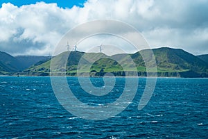 Wind turbines on hill from blustery Cook Strait Wellington southern coastline