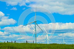 Wind turbines on the horizon of the Oklahoma Prarie under a cloudy blue sky