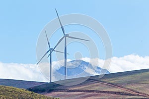 Wind turbines with mountains and clouds in the background