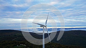 Wind turbines in the mountains during sunrise and thick morning fog in the valley. Wind farm producing green energy.