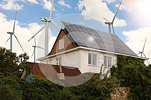 Wind turbines near house with solar panels on roof. Alternative energy source