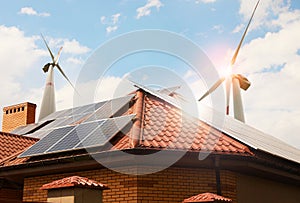 Wind turbines near house with solar panels on roof. Alternative energy source