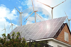 Wind turbines near house with solar panels on roof. Alternative energy source