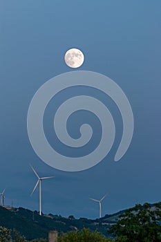 Wind turbines at night on the hill in a full moon night