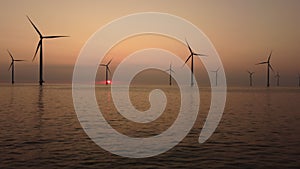 Wind turbines offshore producing electricty during sunset