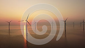 Wind turbines offshore producing electricty during sunset